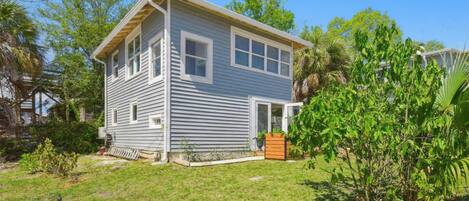 A two-story house with a front porch, a small garden, and a wooden deck.
