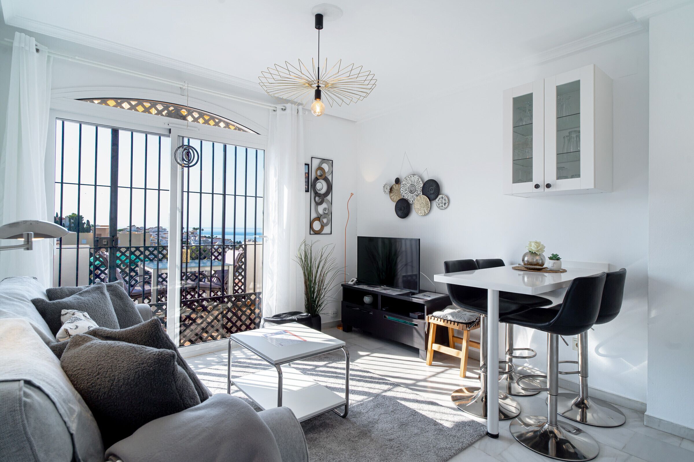 A modern living room with a sofa, a dining table with chairs, a TV, and decorative wall art.