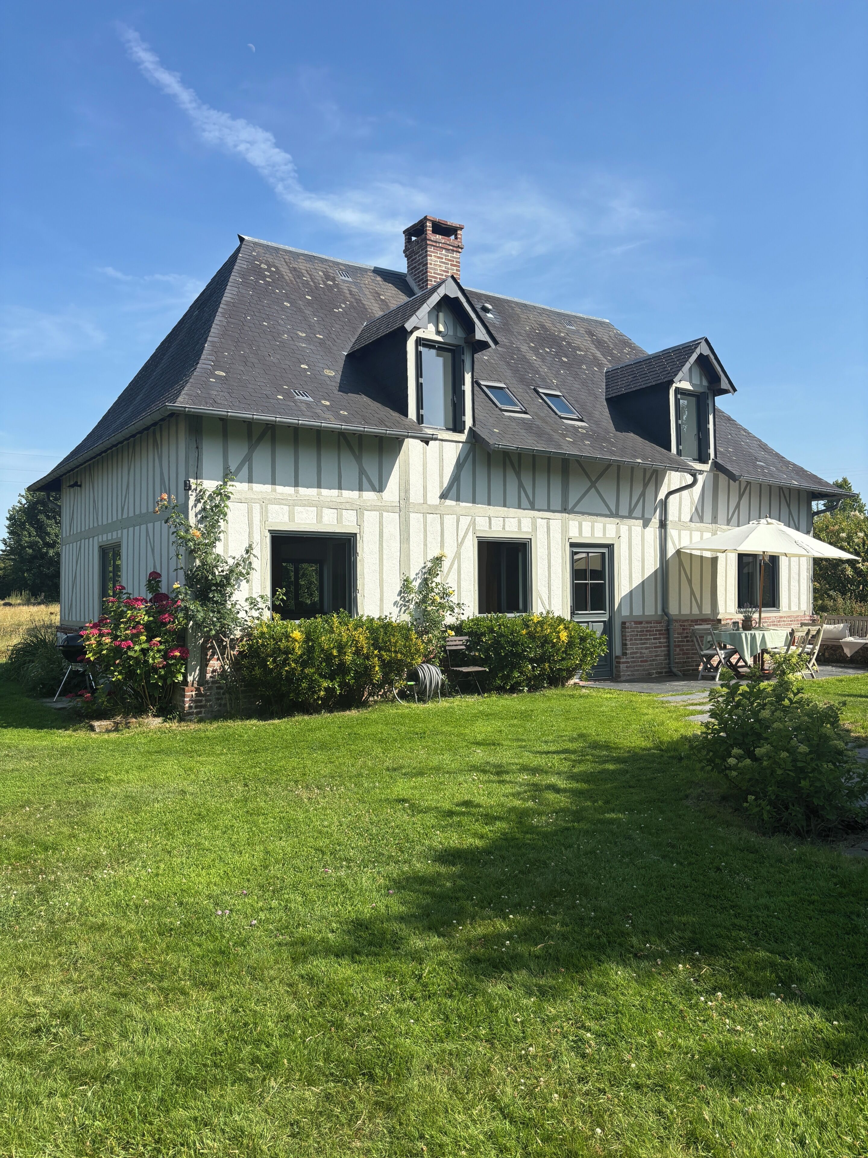 Une grande maison avec un toit en pente, de nombreuses fenêtres et une cheminée.