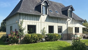 Une grande maison avec un toit en pente, de nombreuses fenêtres et une cheminée.