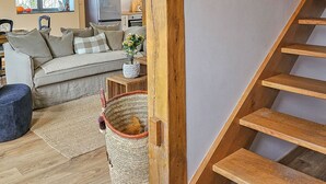 Un escalier avec des marches en bois menant à un palier, un canapé, une petite table avec un vase et une fenêtre donnant sur l’extérieur.