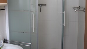 A bathroom with a glass-enclosed shower, a white sink, and a small shelf. - 3. standard double room (Lena) in a quiet location in Görlitz (Görlitz)
