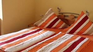 A single bed with striped bedding in a room with yellow walls. - 3. standard double room (Lena) in a quiet location in Görlitz (Görlitz)