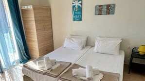Un llit doble amb roba de llit blanca, una petita taula de nit amb una làmpada groga i dues decoracions murals.