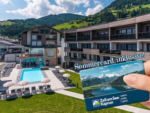 Un hôtel moderne doté d’une piscine, de chaises longues et offrant une vue sur une montagne boisée.
