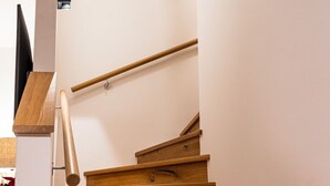 Eine Holztreppe mit Handlauf, einem Wandbild und einem Flachbildfernseher.