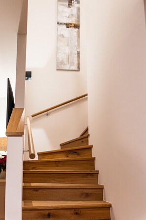 A wooden staircase with a handrail, a wall-mounted artwork, and a flat-screen TV. - 3_SPA Deluxe Panorama 522 by Interhome (Zell am See)