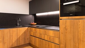 Eine moderne Küche mit schwarzer Arbeitsplatte, Holzschränken, einer Edelstahl-Spüle und einem eingebauten Backofen.