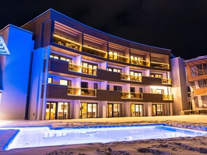 Un hotel a più piani con balconi, una piscina e una zona spiaggia sabbiosa.