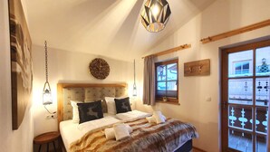 Un dormitorio con cama, lámpara colgante, ventana con cortinas y cabecera de madera.