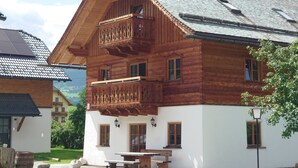 A wooden chalet with a balcony, a dining area, and a white exterior. - 6_ALP - Hochgolling 1  - Loft Apartment by Interhome (Mariapfarr)