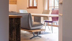 A modern interior with a wooden ceiling, a dining area with a table and chairs, and a window with curtains. - 6_ALP - Penthouse Preber by Interhome (Mariapfarr)