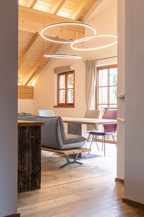 A modern interior with a wooden ceiling, a dining area with a table and chairs, and a window with curtains. - 6_ALP - Penthouse Preber by Interhome (Mariapfarr)