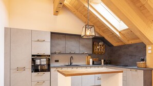 A modern kitchen with a central island, wooden beams, and a skylight. - 6_ALP - Penthouse Preber by Interhome (Mariapfarr)