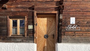 En stuga byggd av trästockar, med en trädörr, ett fönster och en skylt med texten ”Chalet Grosseck”.