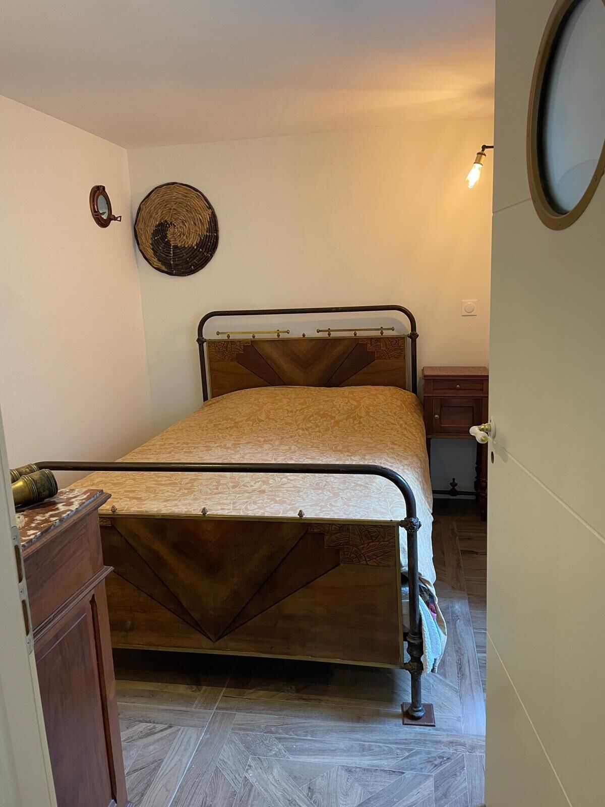 A bedroom with a bed, a dresser, a mirror, and a wall-mounted light fixture.