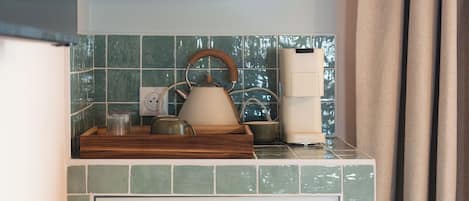 A kitchen with a tiled backsplash, a coffee maker, and a kettle on the counter.