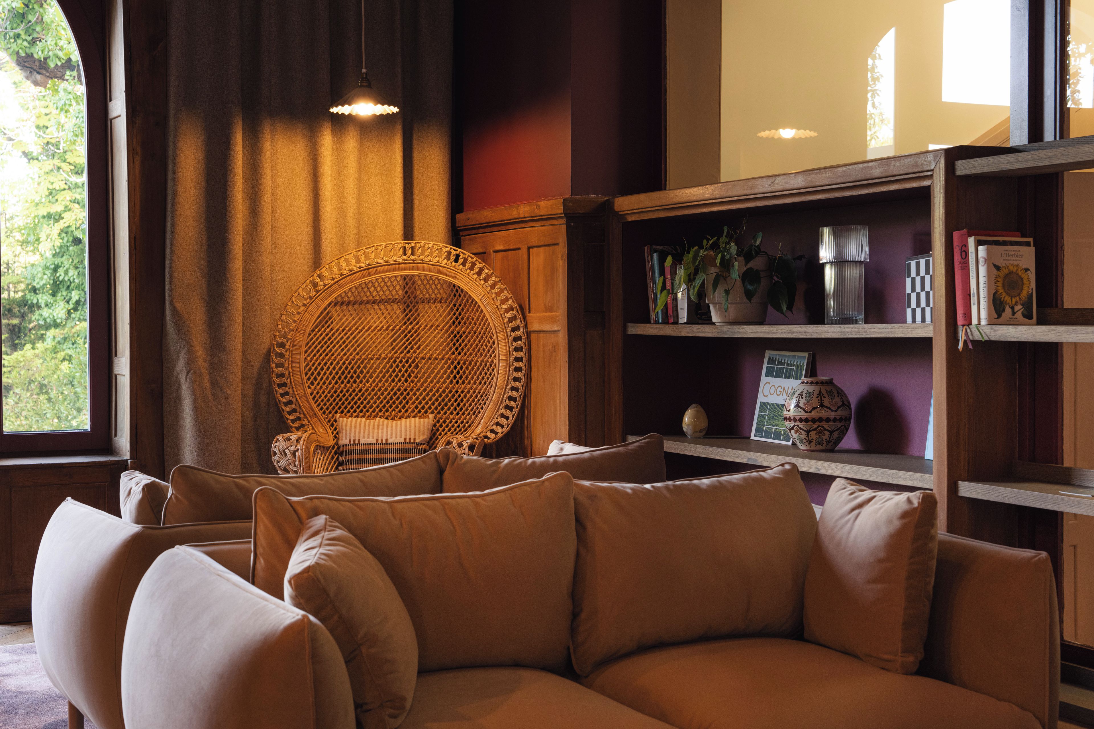 Una sala de estar acogedora con un sofá, un sillón de mimbre y una estantería.