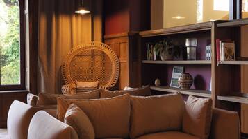 Una sala de estar acogedora con un sofá, un sillón de mimbre y una estantería.