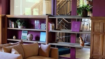 Een woonkamer met een bank, fauteuil en een boekenkast.