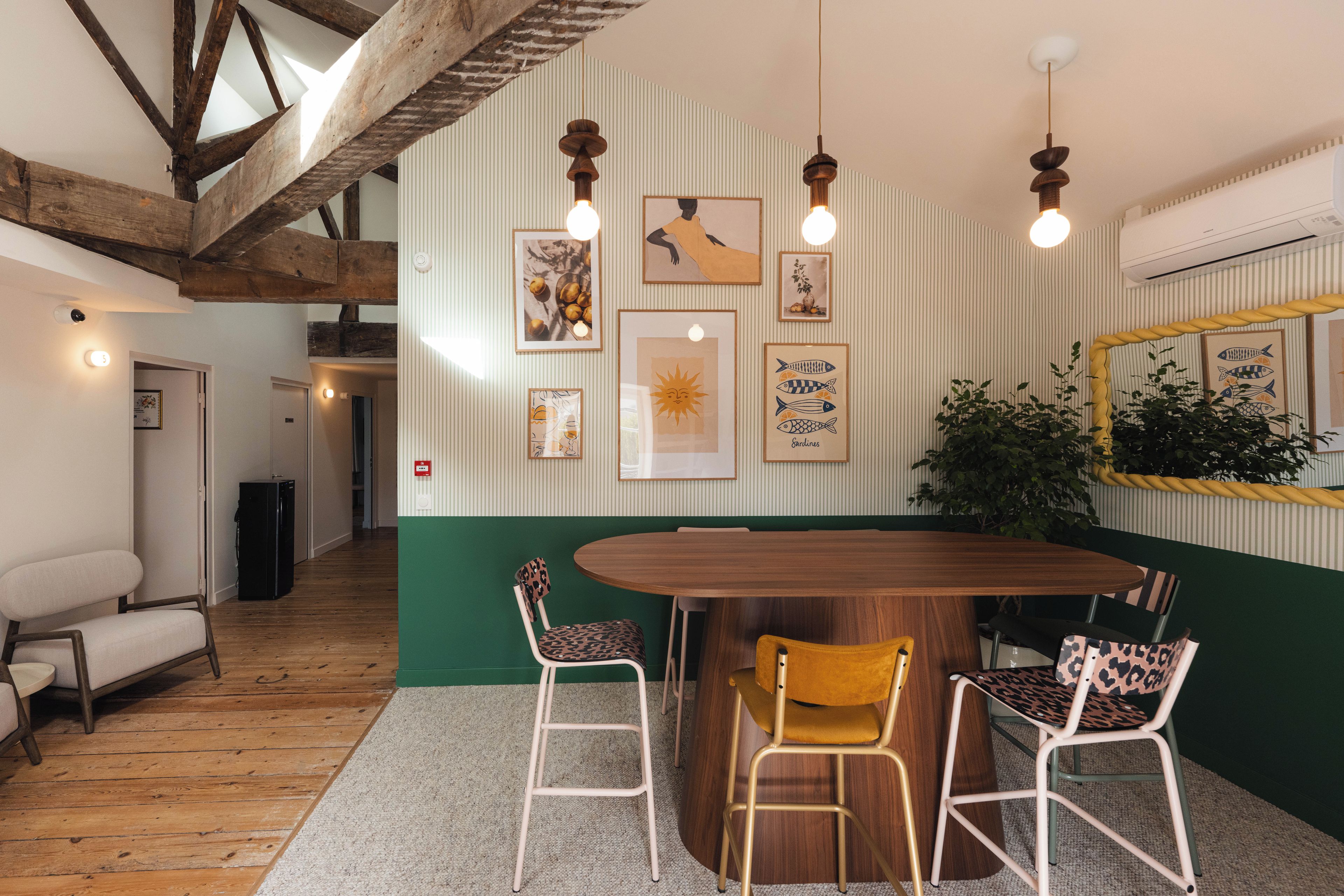 Un comedor con una mesa de madera, sillas y una pared de acento verde.