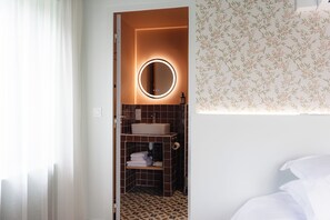 A bathroom with a round mirror, a sink, and a toilet. - Héméra Cognac (Cognac)