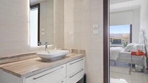 Un baño moderno con un espejo grande, un lavabo sobre encimera y una encimera de madera.