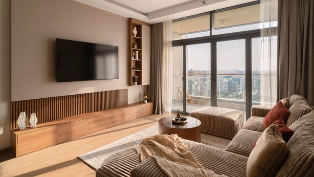 A modern living room with a flat-screen TV, a wooden console, a round coffee table, and a sofa with cushions. - AEON Towers Lucky Cloud #606 - nesty (6th of October City)