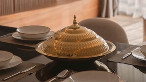 A dining area with a table set for four, a decorative centerpiece, and a television mounted on the wall. - AEON Towers Lucky Cloud #606 - nesty (6th of October City)