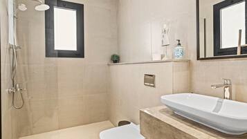 Ein modernes Badezimmer mit Badewanne, Toilette, Dusche und einem großen Spiegel.