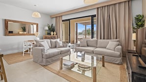 Ein modernes Wohnzimmer mit zwei Sofas, einem Glastisch und einem großen Spiegel.