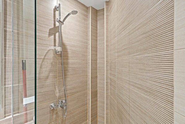 A modern shower with a glass enclosure and a wall-mounted faucet.