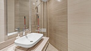 A modern bathroom with a large mirror, a white sink, and a shower area.
