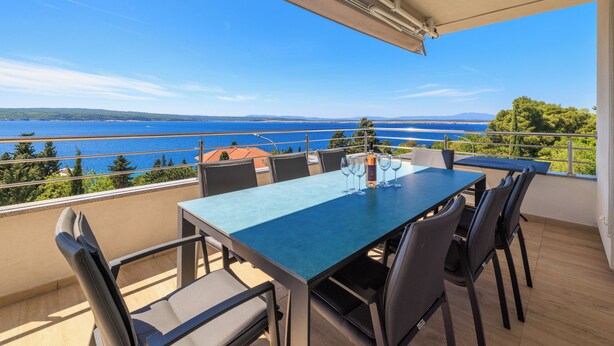 En balkon med et bord og stole med udsigt over vandet.