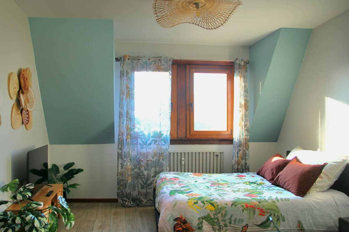 A bedroom with a bed, a window, a radiator, and a ceiling light fixture.