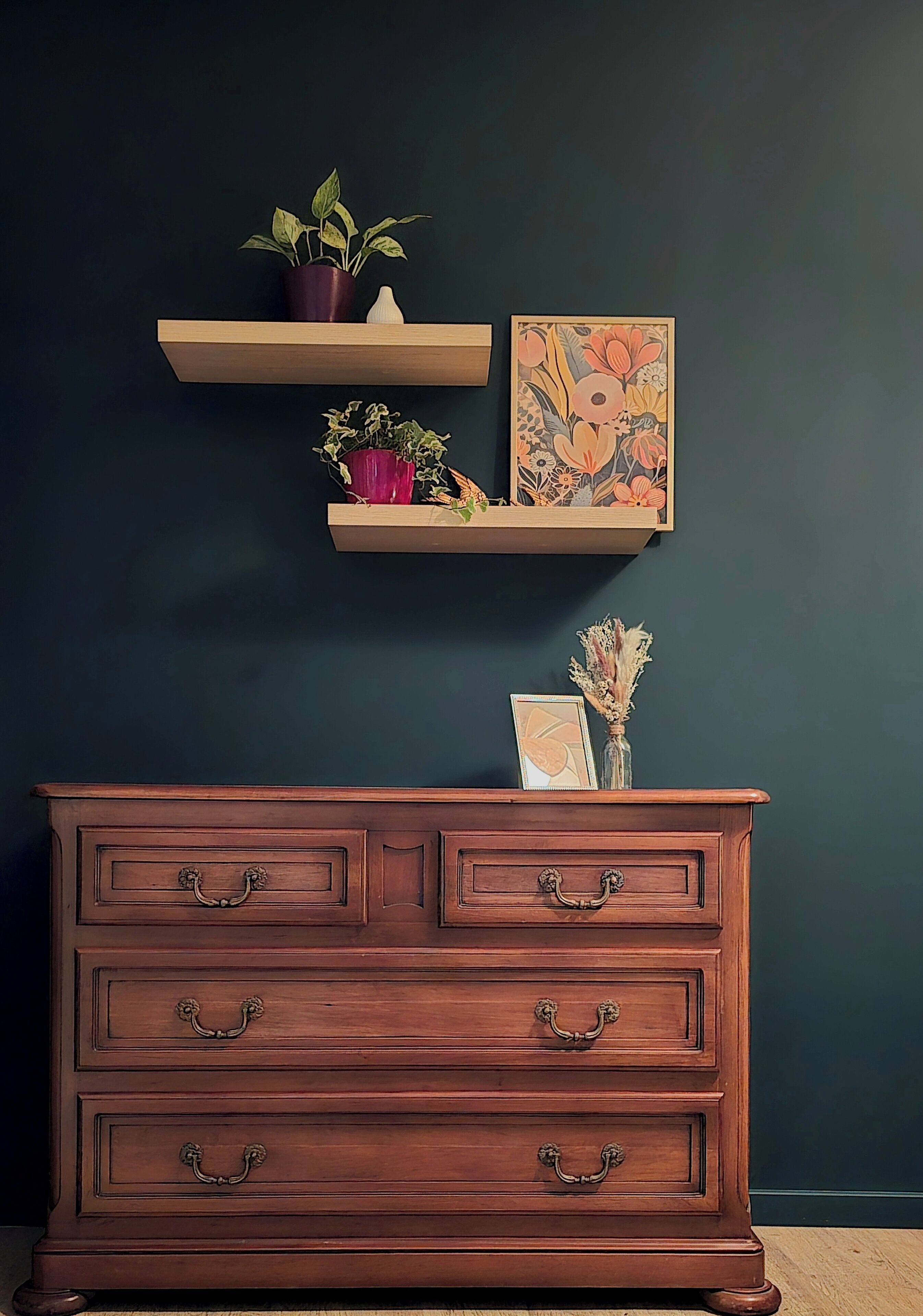 A wooden dresser with drawers and ornate handles, positioned against a dark wall.