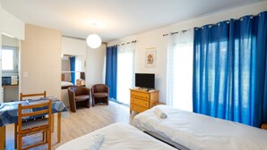 A hotel room with two beds, a desk with a chair, a TV, and a wardrobe.