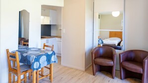 A compact living space with a dining area, kitchenette, and a bed with a headboard.