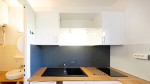 A compact kitchen with a sink, countertop, and cabinets.