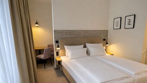 Een hotelkamer met een bed, twee nachtkastjes, een stoel en een bureau.