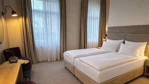 Een hotelkamer met een tweepersoonsbed, een bureau, een stoel en een lamp.