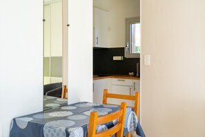 A dining table with a patterned tablecloth, a wooden chair, and a kitchen area with cabinets and a window.
