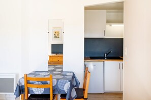 Una cocina compacta con refrigerador, lavamanos y armarios de madera.