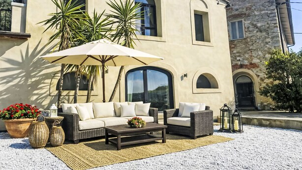 A building with a patio area featuring outdoor furniture, a large umbrella, and potted plants. - Villa Casale Belvedere by Interhome (Monsummano Terme)
