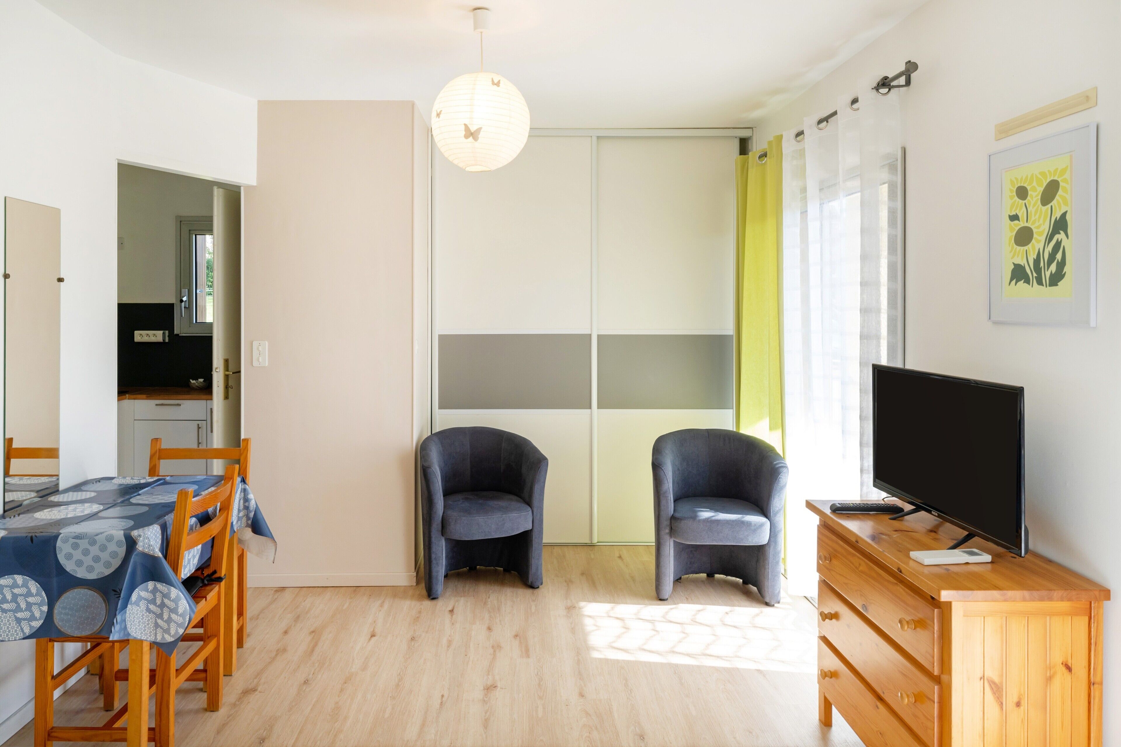 A room with a dining table, two chairs, a TV on a wooden cabinet, and a sliding closet door.
