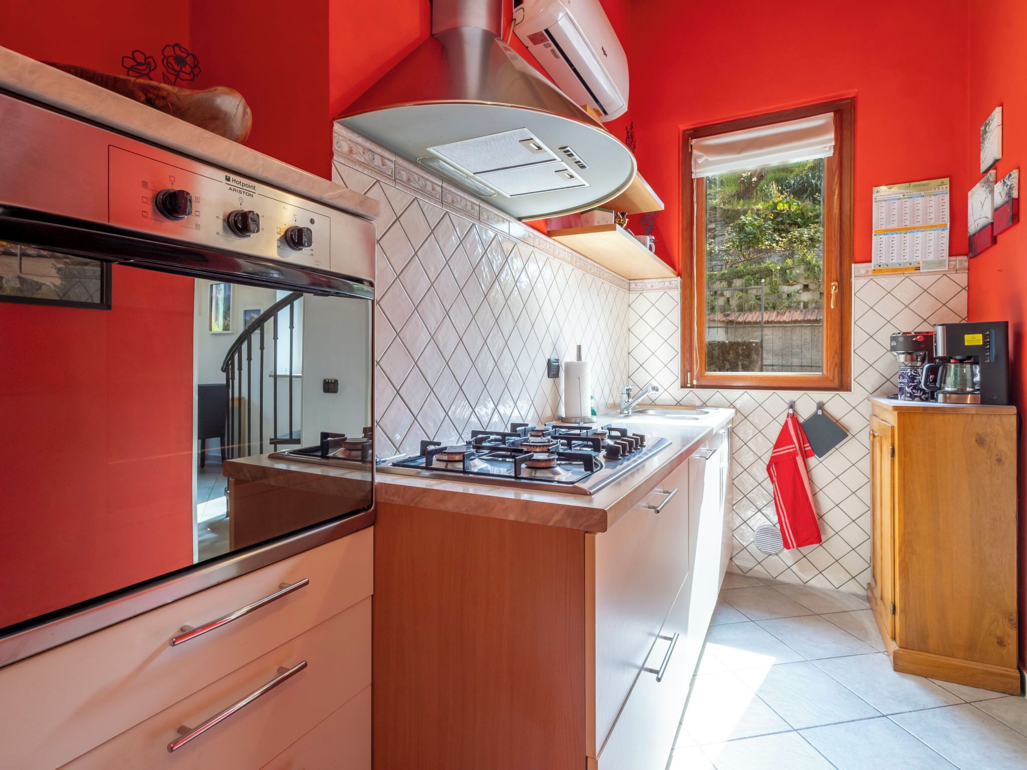 A kitchen with a gas stove, oven, and a window with a view of greenery.