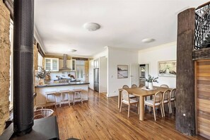 Una cocina amplia con una isla central, suelo de madera y un comedor con mesa y sillas de madera.