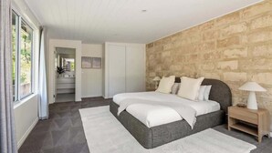 Ein Schlafzimmer mit einem großen Bett, einem Nachttisch und einer Steinwand.