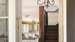 Eine Holztreppe führt zu einer Küche mit weißen Schränken und einer hängenden Lampe.