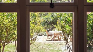 A window with a view of a garden and outdoor seating area.